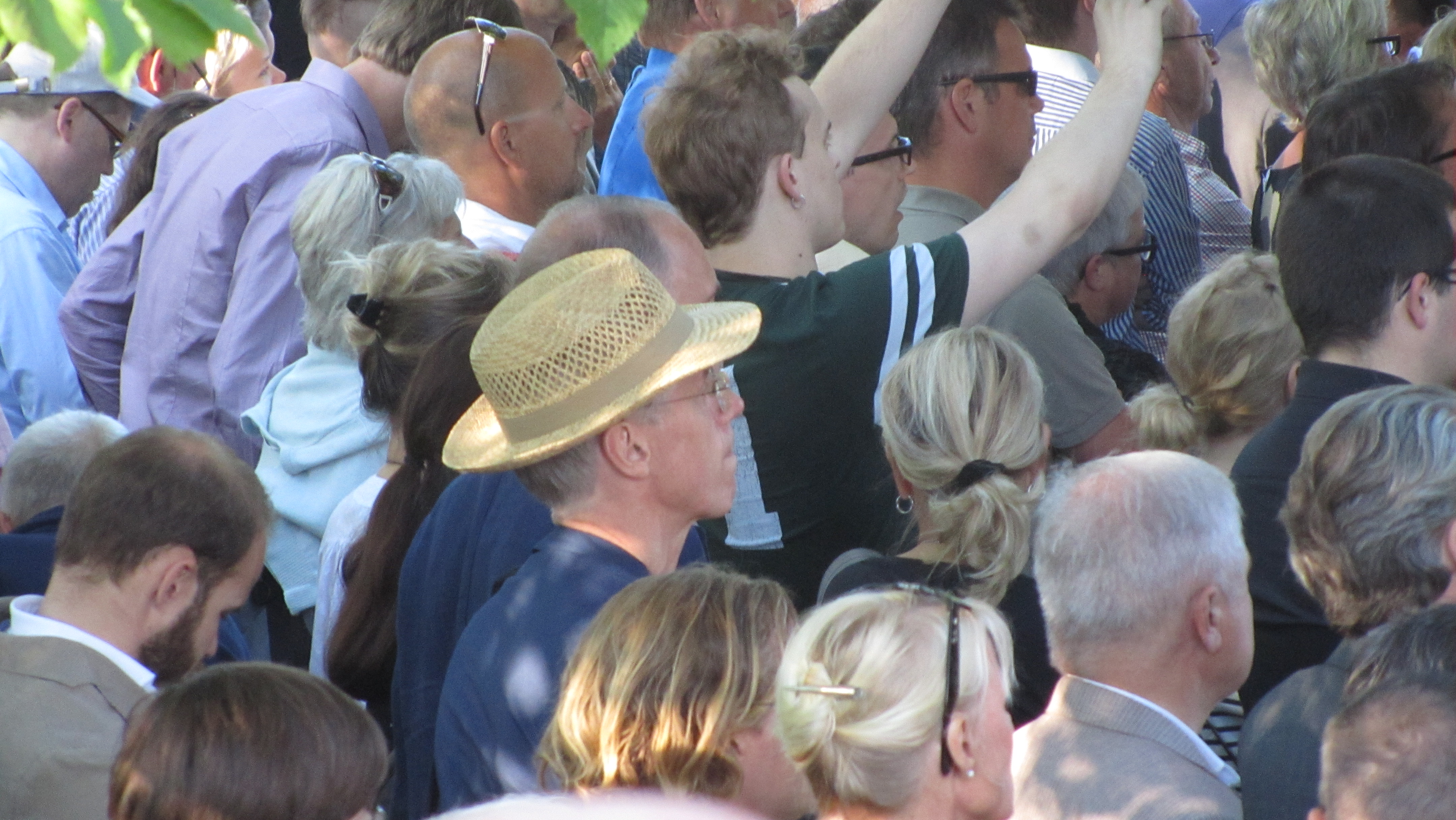En man i hatt lyssnar till partiledartal i Almedalen.